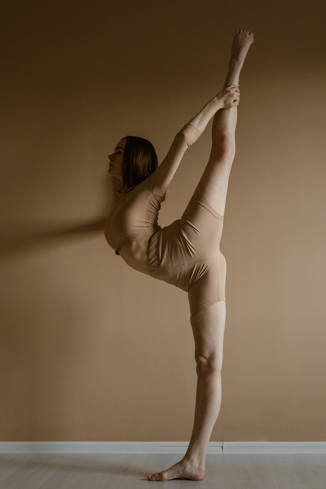 Side View of a Flexible Woman in Beige Leotard Raising Her Leg